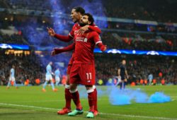 Mohamed Salah of Liverpool celebrates with Virgil van Dijk as a blue flare is thrown on to the pitch by the Liverpool fans